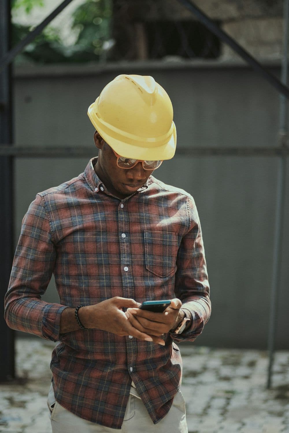 A site manager in a hard hat checking his phone